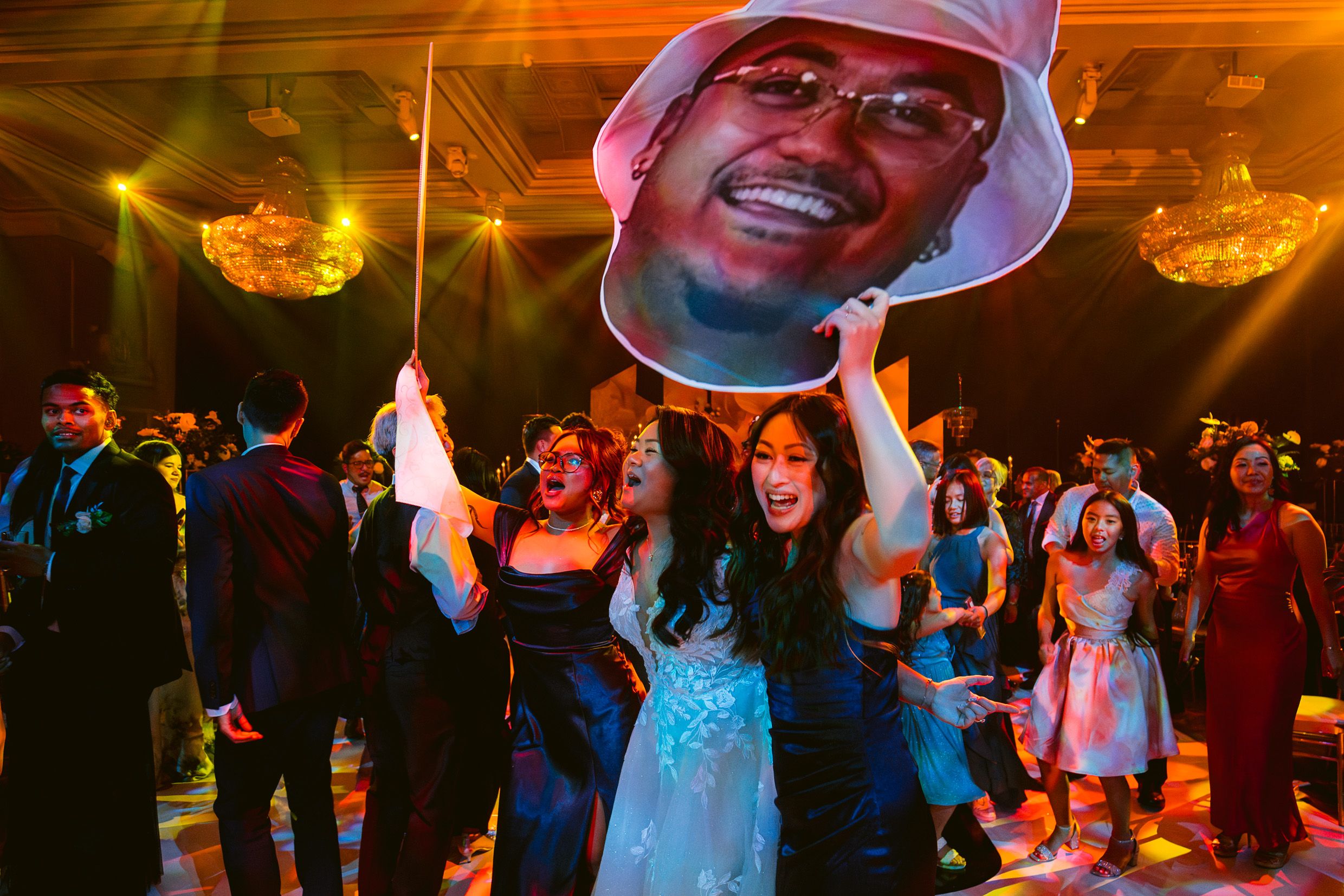 Wedding guests dancing and celebrating on a vibrant dance floor with colorful lighting effects.