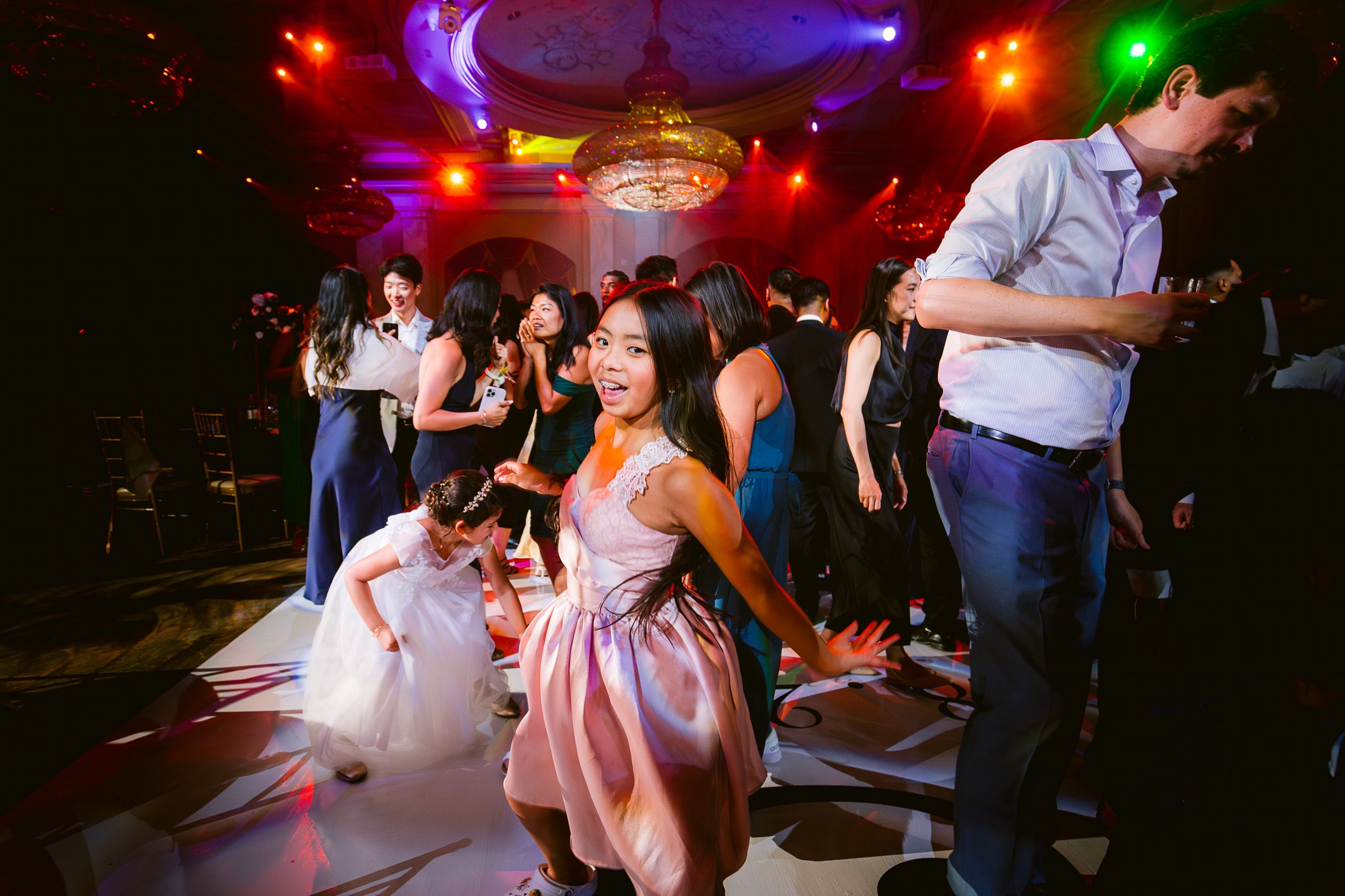 People dancing on a lively dance floor illuminated by colorful disco lights at a festive celebration.