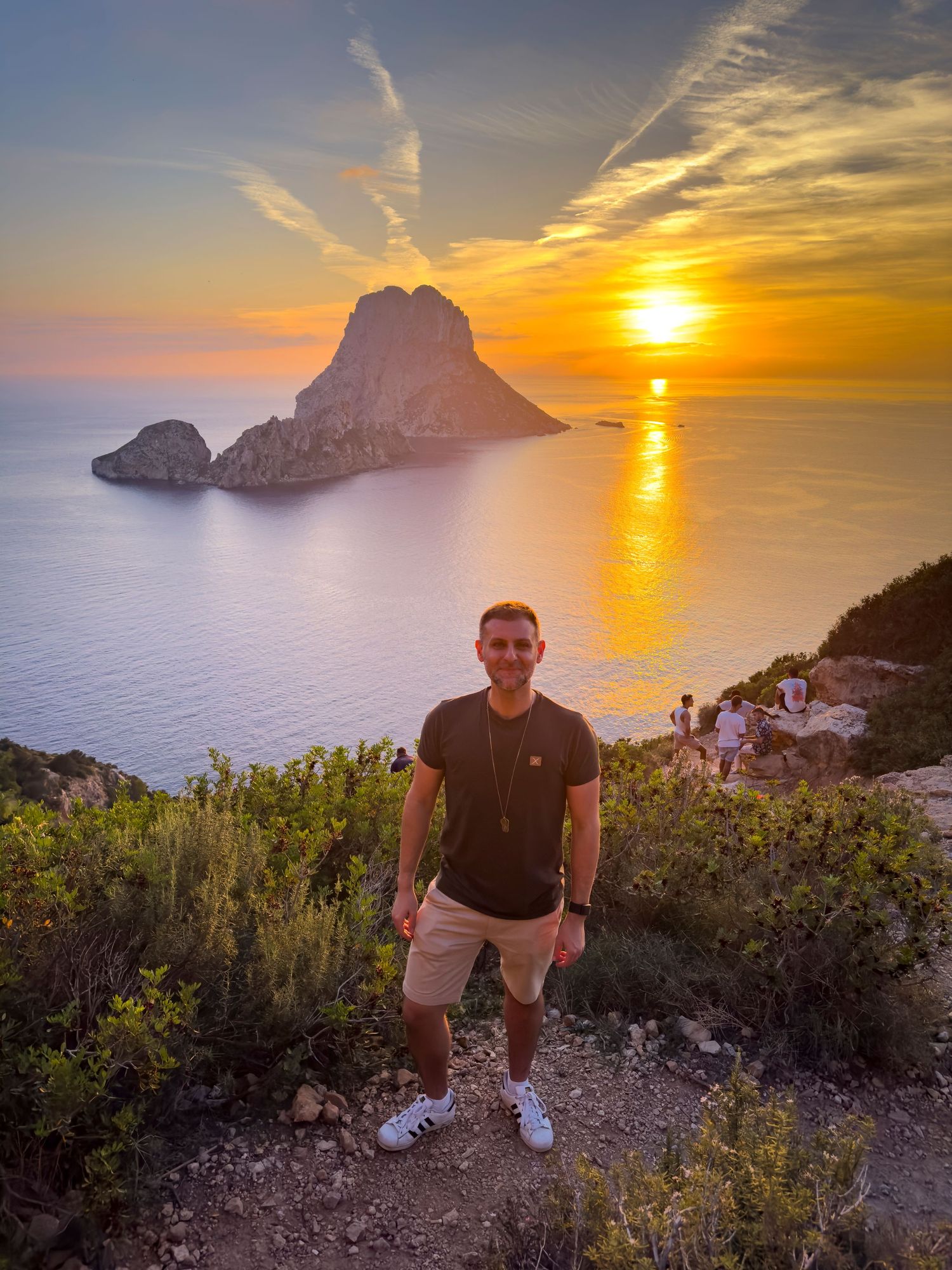Stunning sunset view over Es Vedra island in Ibiza with dramatic orange sky and Mediterranean Sea reflections. Lee Charlton is featured.