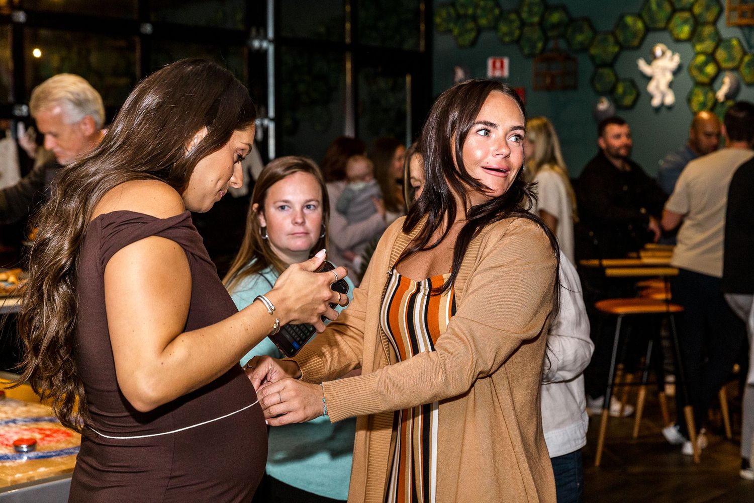 Two friends dancing and laughing together at a lively bar with festive decor in the background.