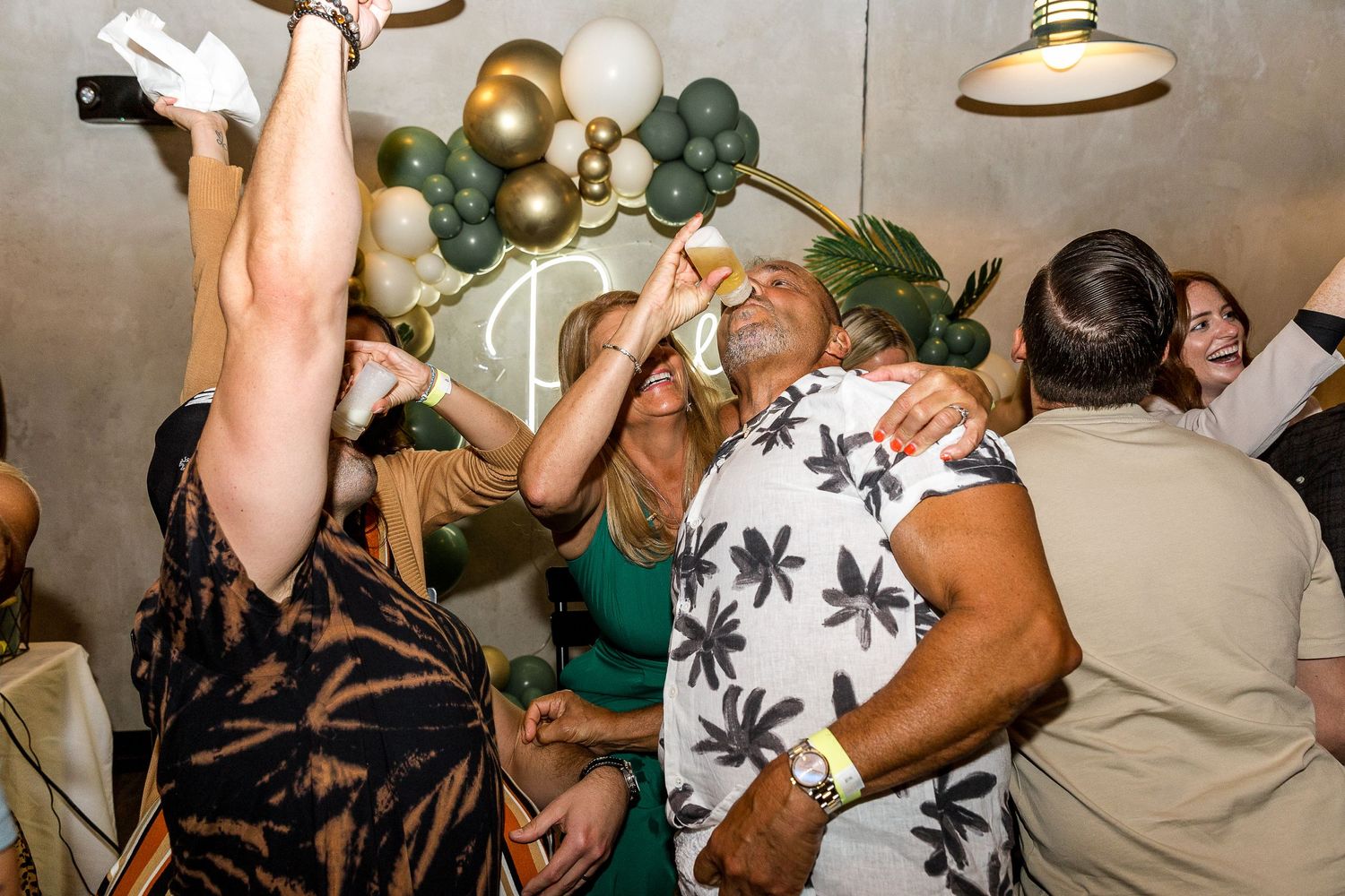 Energetic party scene with people dancing under balloon decorations.