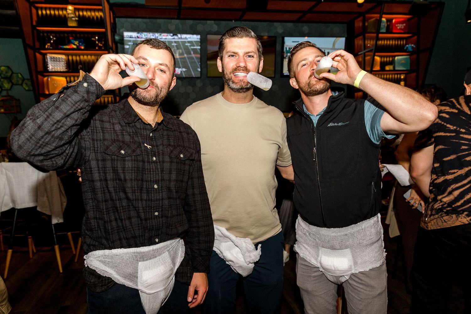 Three friends taking shots together at a bar.