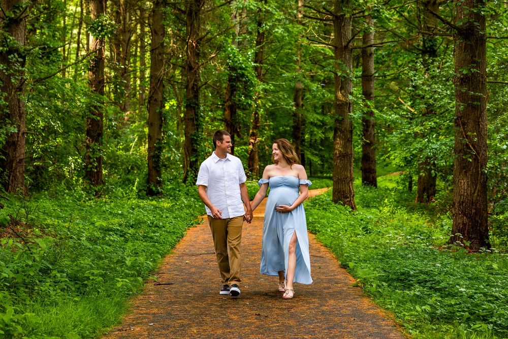 Two people walking together on a scenic forest path surrounded by lush green trees and vegetation.