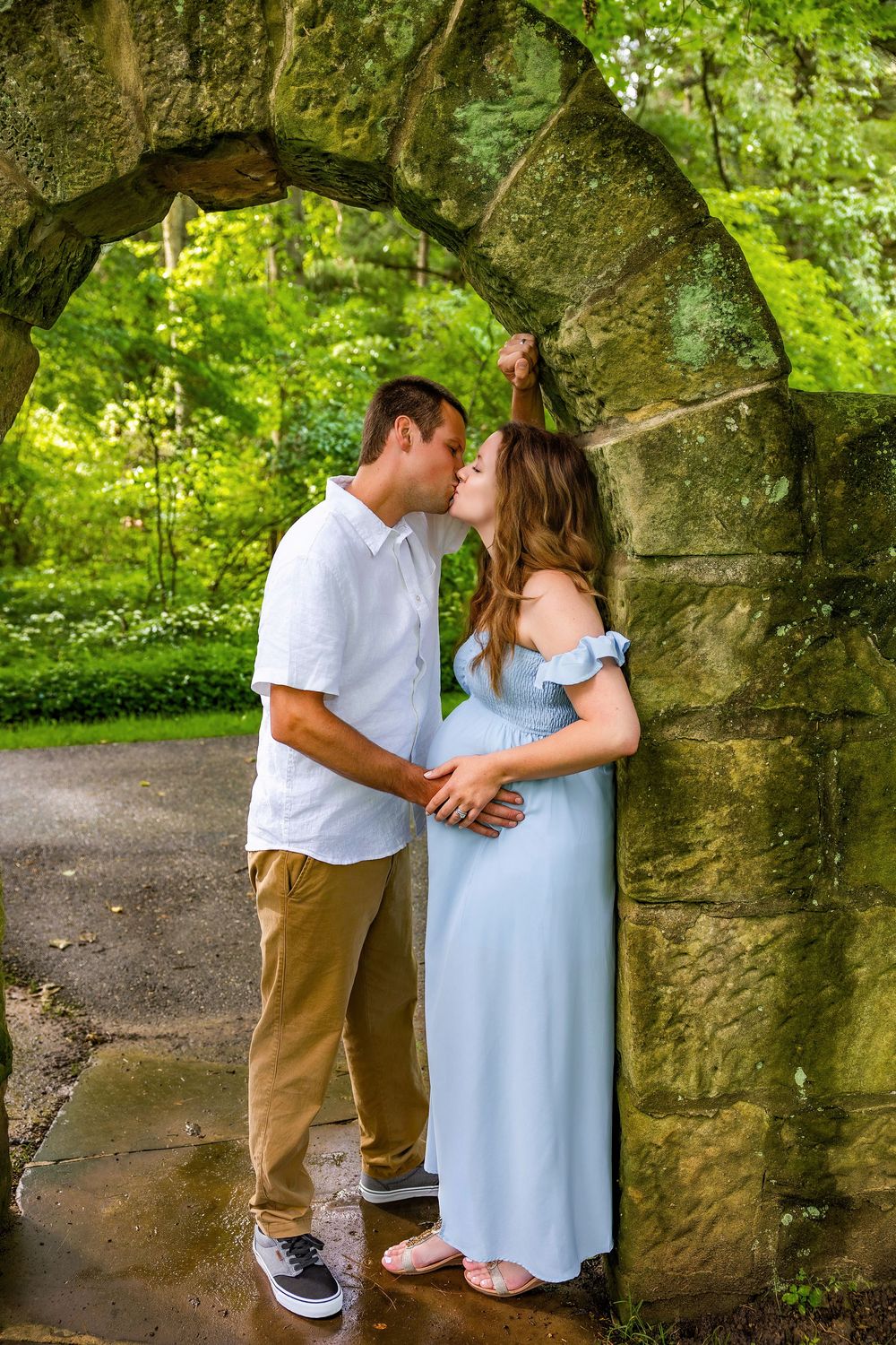 A romantic outdoor photoshoot with a couple sharing tender moments in a lush green garden setting.