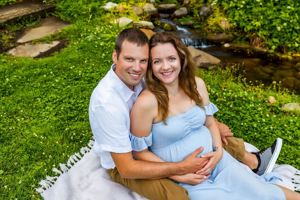 Couple dressed in white and blue share tender moments during an outdoor photo session in a lush garden setting.