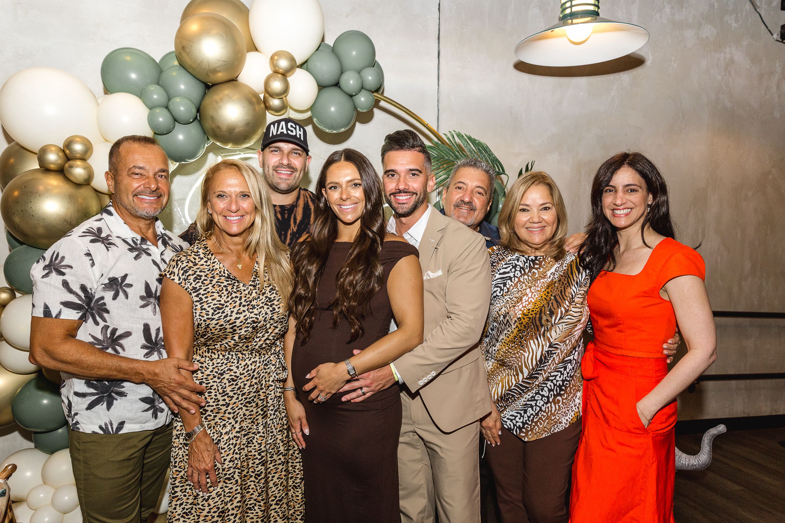 Group photo at celebration with balloon arch and formal attire.