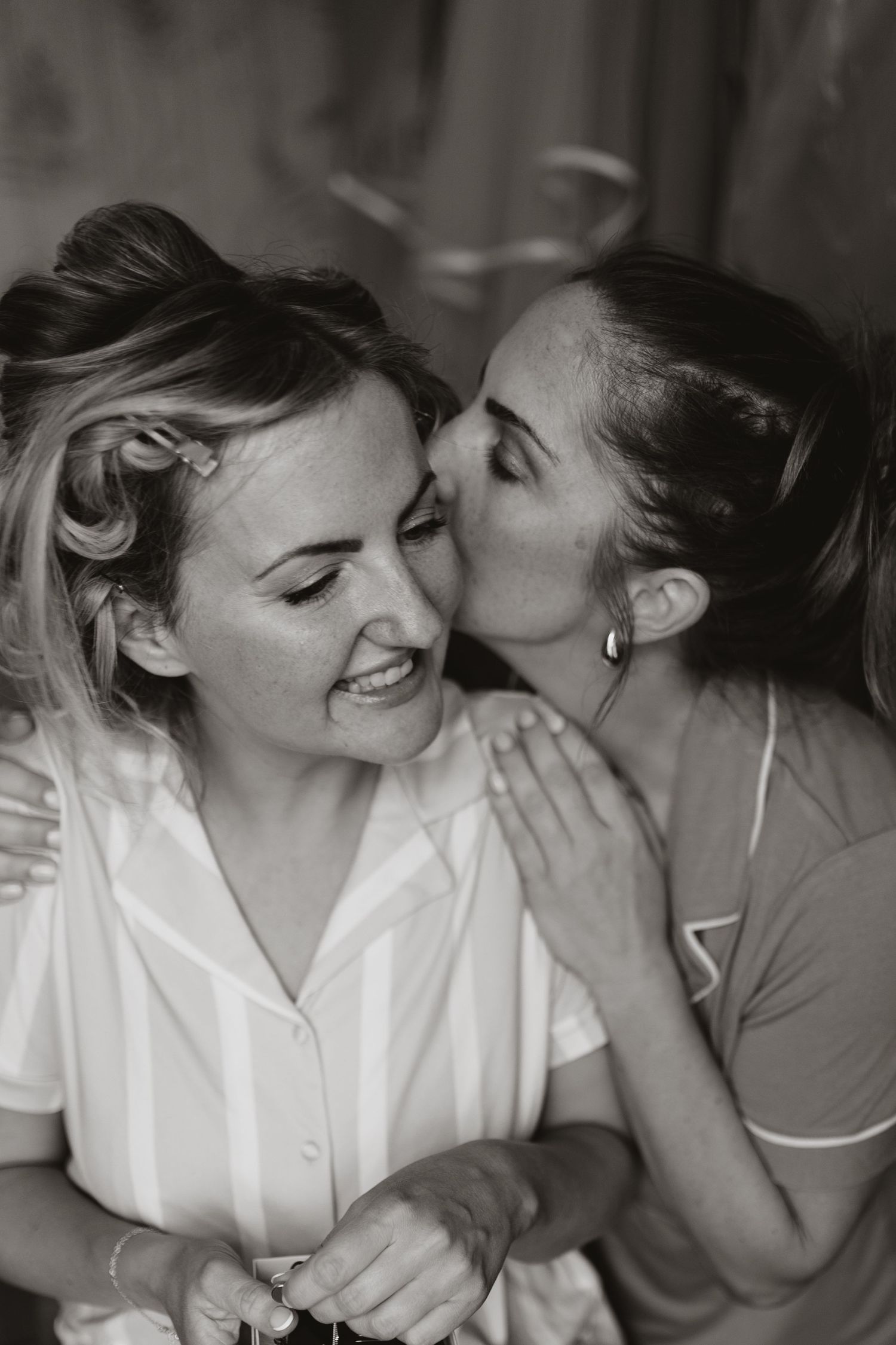A candid black and white photograph captures an intimate moment of shared laughter and affection.