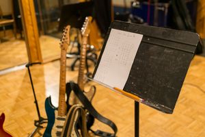 Sheet music stands are arranged in rows on a wooden floor during a musical performance setup.