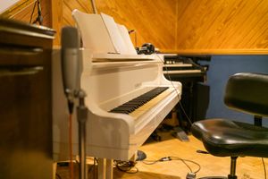 Recording studio interior with polished wooden floors, acoustic panels, and music production equipment in warm lighting.