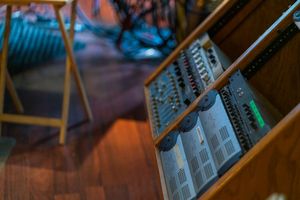 Audio equipment and mixing boards illuminate a dark recording studio workspace with blue and orange lighting.