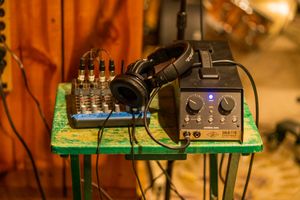 Professional audio headphones and mixer setup on green surface in recording studio environment.