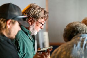 Musicians reviewing content on mobile device during recording session.