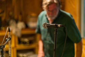 Close-up shot of a studio microphone with someone working in the background.