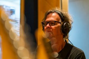 Musician wearing headphones in recording studio with soft bokeh lighting effects.
