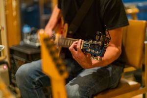 Close-up of hands playing electric guitar during studio recording session.