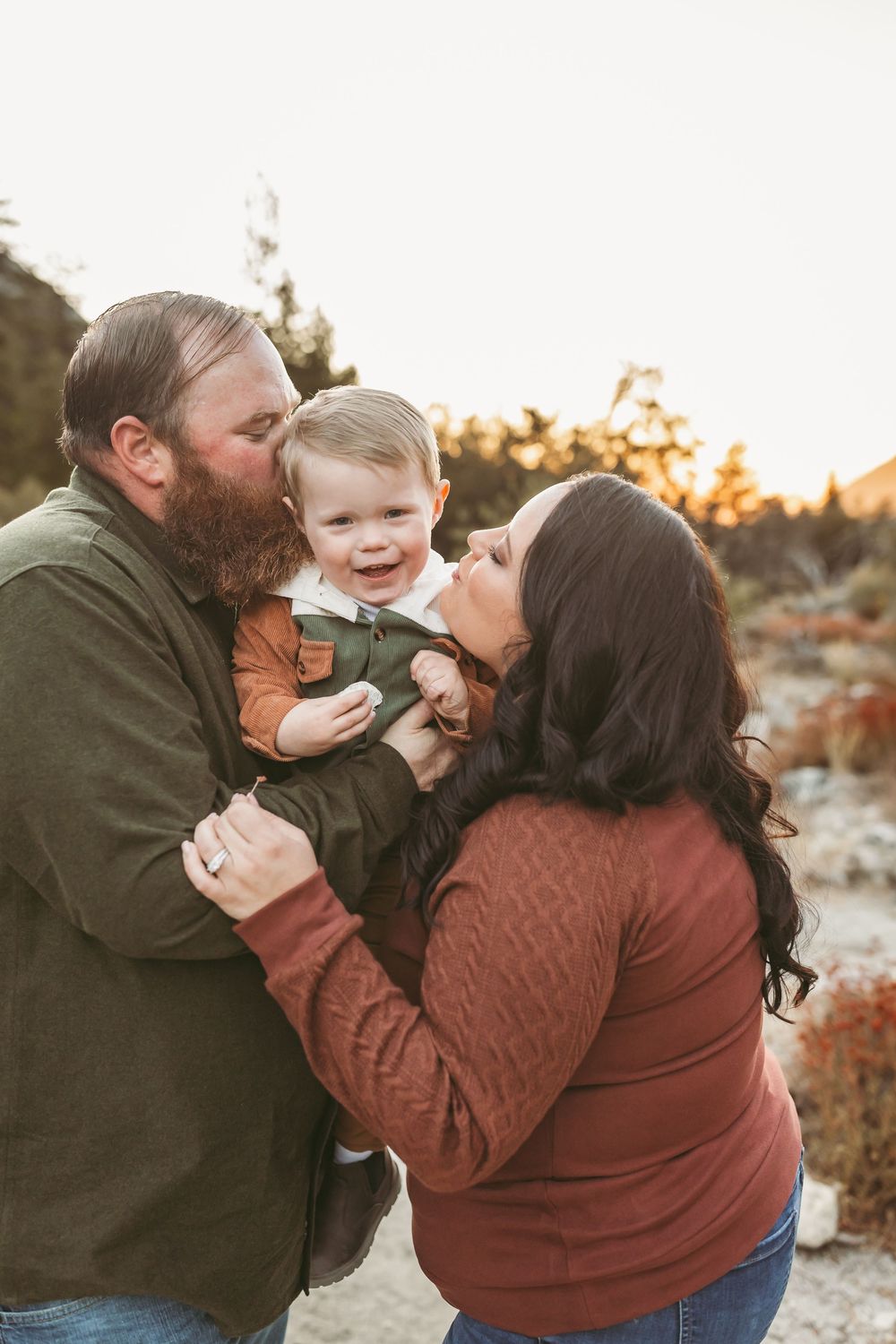 A family shares an intimate moment together outdoors during golden hour sunset in autumn clothing.