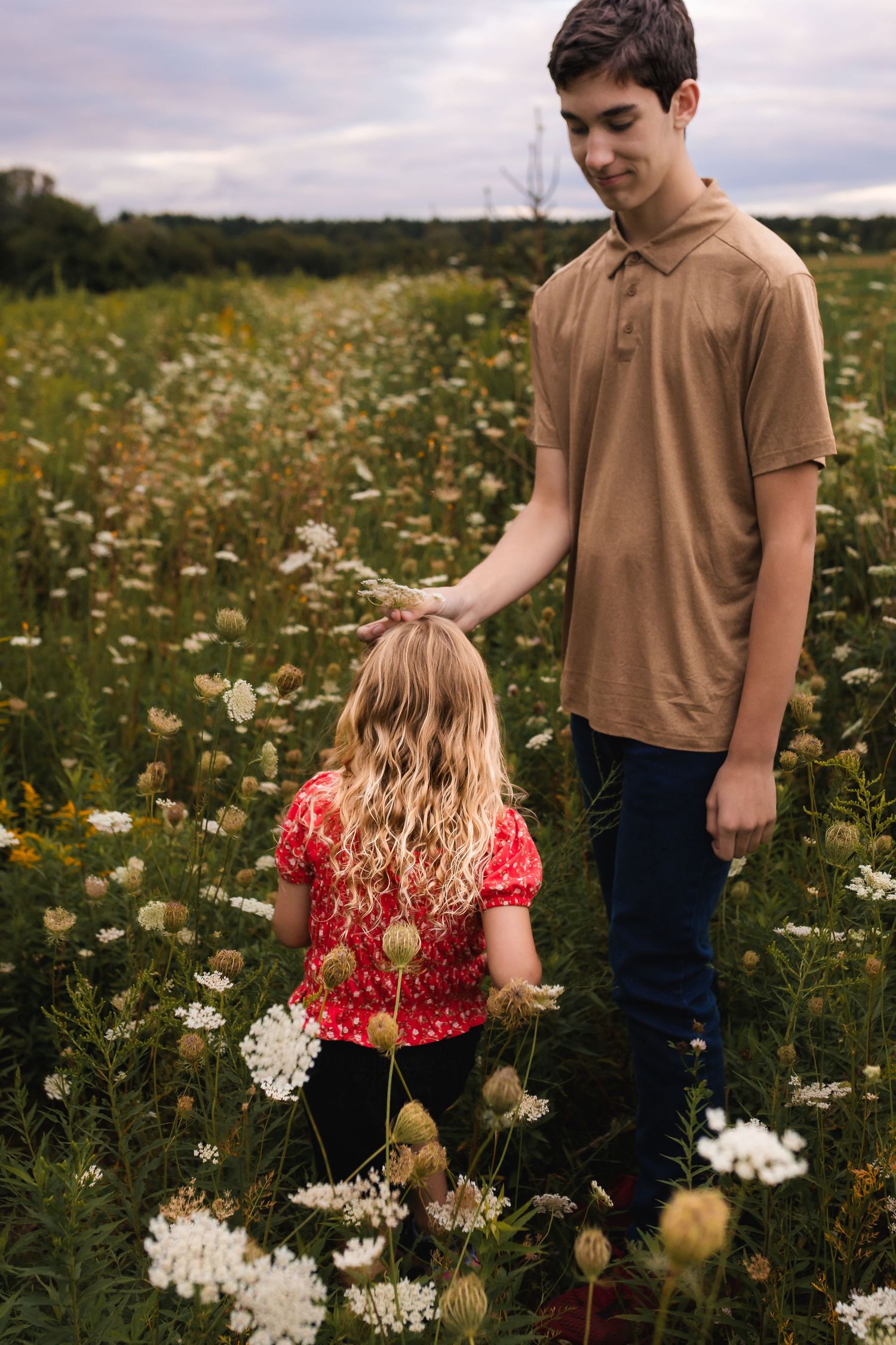 Children explore a blooming wildflower meadow filled with white and yellow daisies on a summer afternoon.