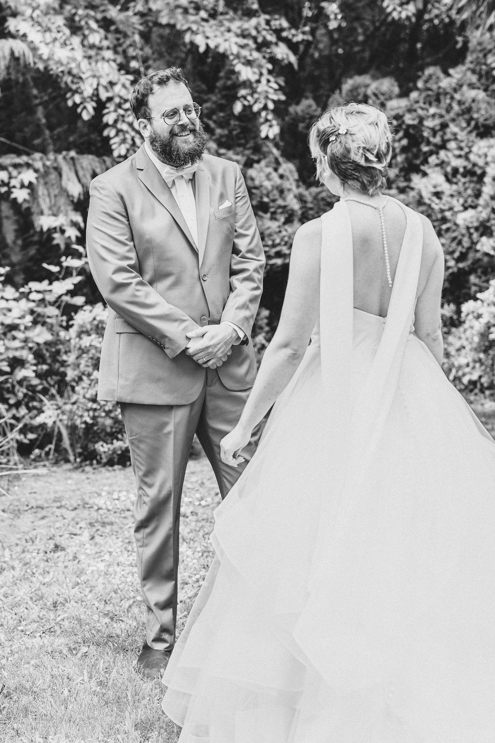 A black and white photo of a wedding couple sharing a special moment in an outdoor garden setting.