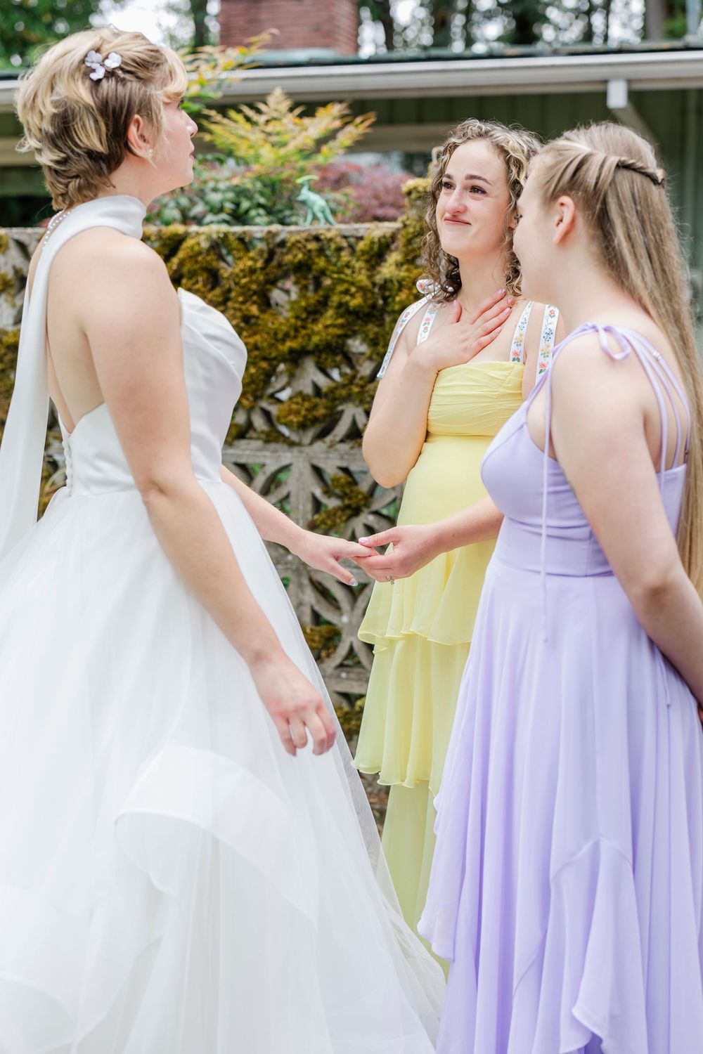 Wedding party members in lavender and pale yellow dresses gather on a porch during a celebration.