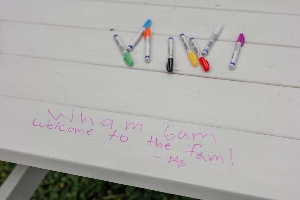 Colorful mini clothespins arranged in a decorative pattern on white lined paper with faint purple writing underneath.