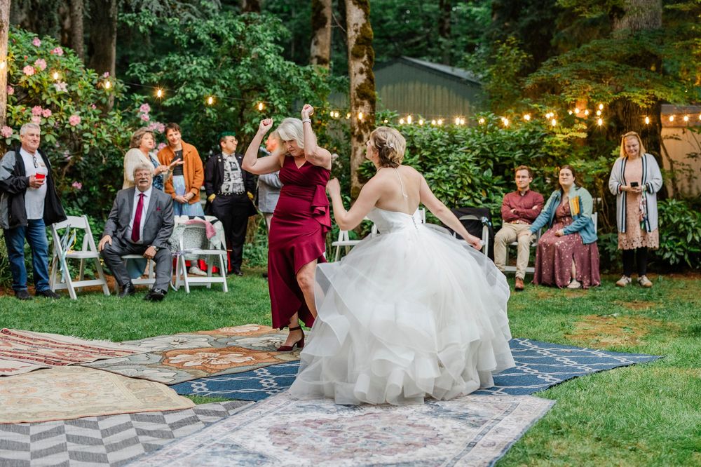 Wedding guests dance and celebrate during outdoor garden reception with string lights and lush greenery.
