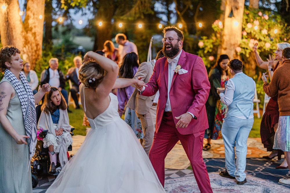 Wedding party and guests celebrate during golden hour at an outdoor summer reception.