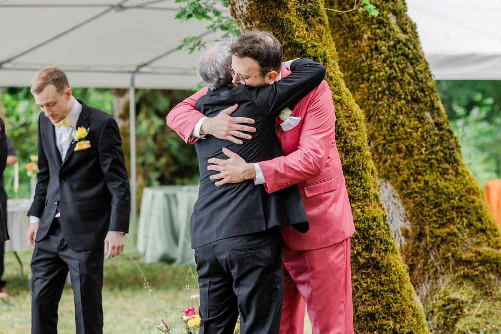 An emotional moment at an outdoor wedding ceremony with attendees in formal attire.