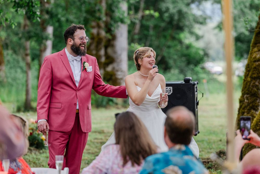 A couple share a joyful moment during their outdoor wedding ceremony surrounded by greenery and guests.
