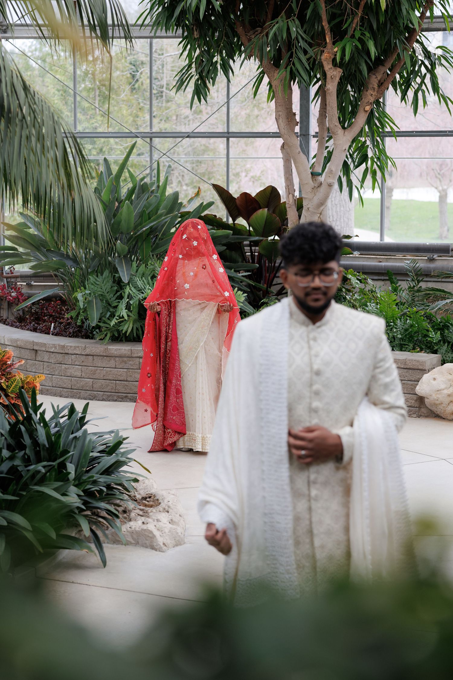 Traditional South Asian wedding ceremony in a greenhouse setting with lush tropical plants.
