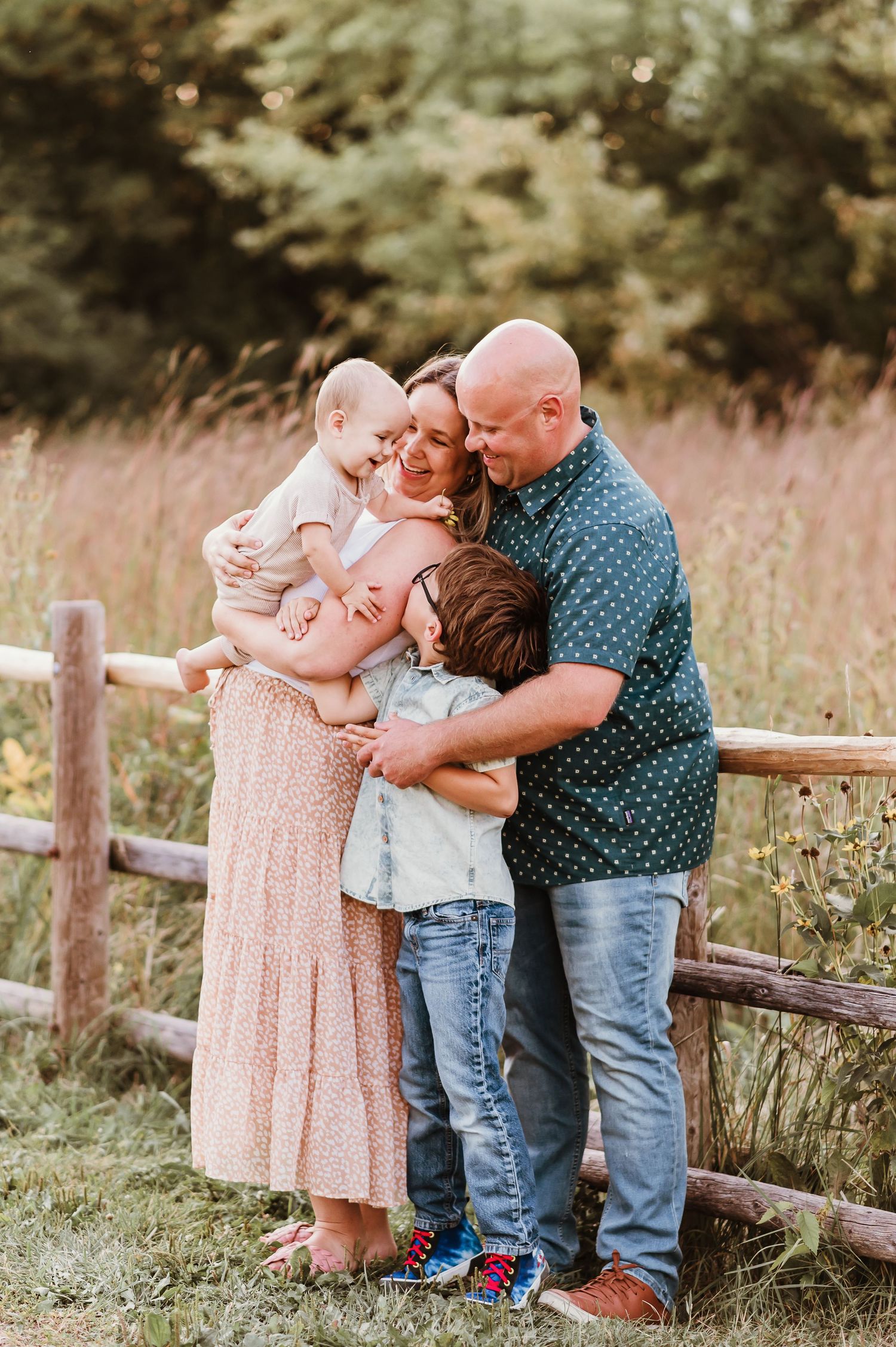 parents snuggling with their children outside against a fence