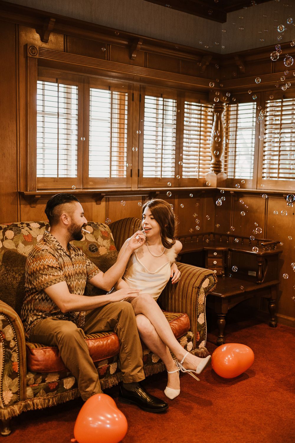 Three sepia-toned connected photos showing couples relaxing on retro furniture with orange spherical objects in a lounge setting.
