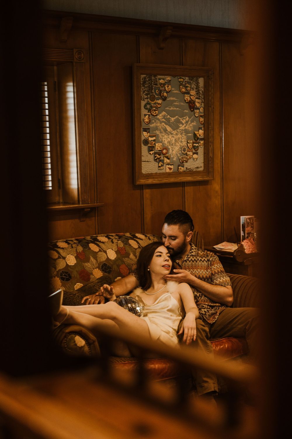 A moody boudoir photoshoot series in warm amber lighting with vintage decor and furniture creating an intimate atmosphere.