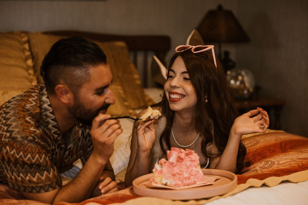 A couple shares an intimate dessert moment at a restaurant while enjoying a slice of pink cake together.