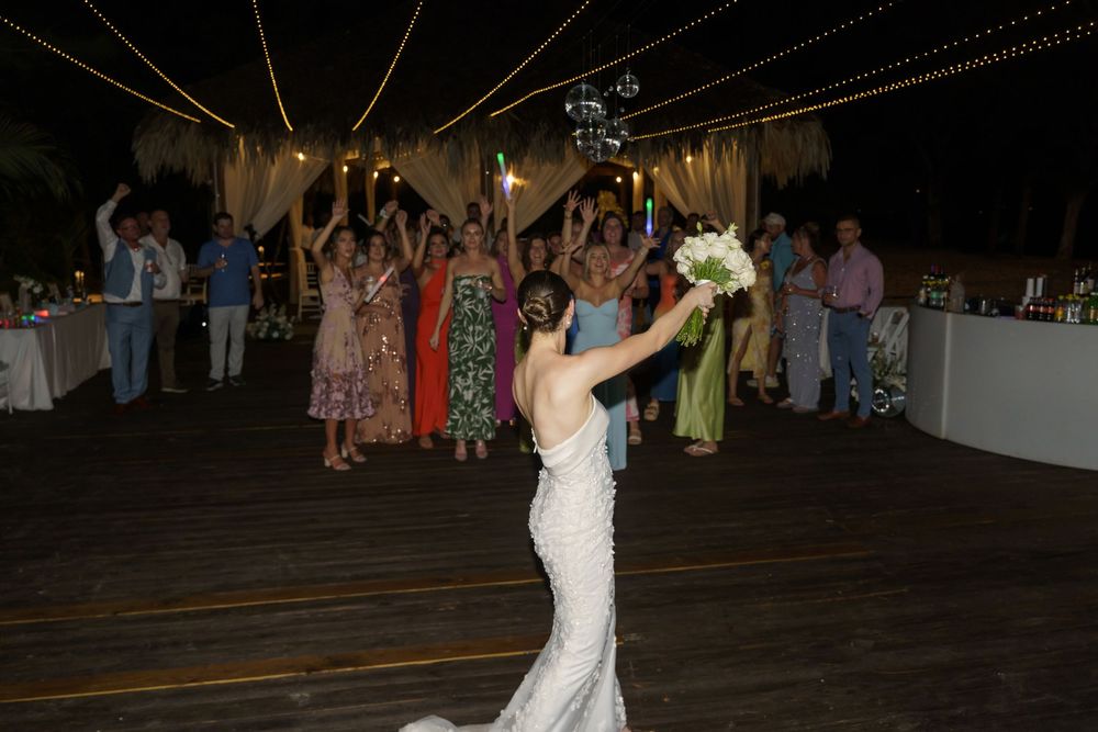 Wedding couple sharing their first dance surrounded by guests on a dimly lit dance floor.