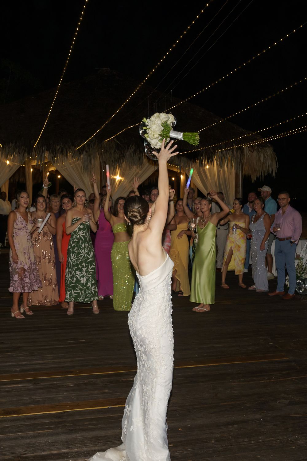 A sequence shows a person in a white wedding dress dancing and celebrating under string lights at an outdoor reception.