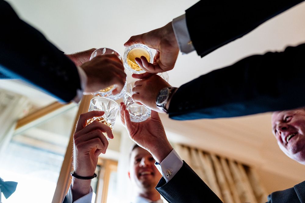 People raising shot glasses together for a celebratory group toast at a social gathering event.