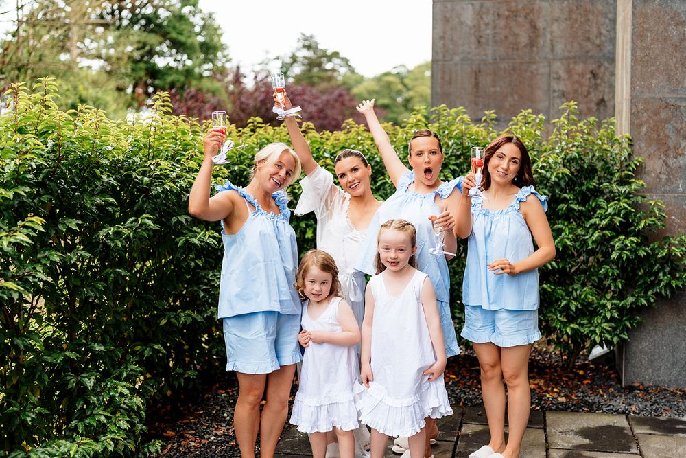 A family wearing coordinating blue and white outfits poses together in a garden setting for casual lifestyle photos.