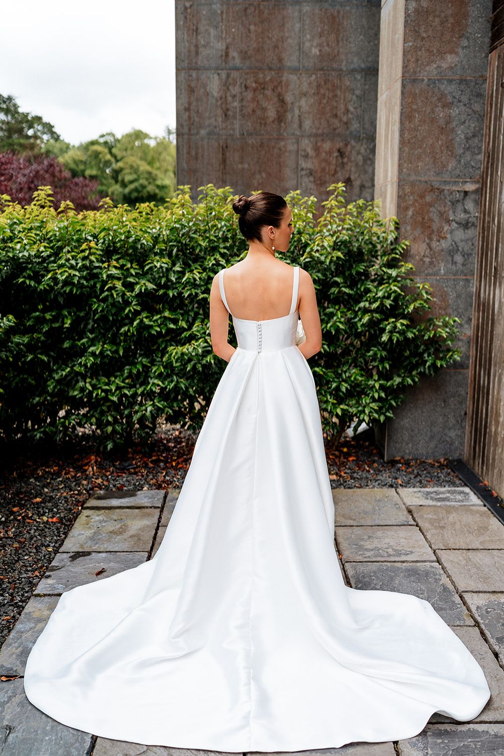 A series of bridal portraits showing the flowing train of a white wedding dress against stone columns and greenery.
