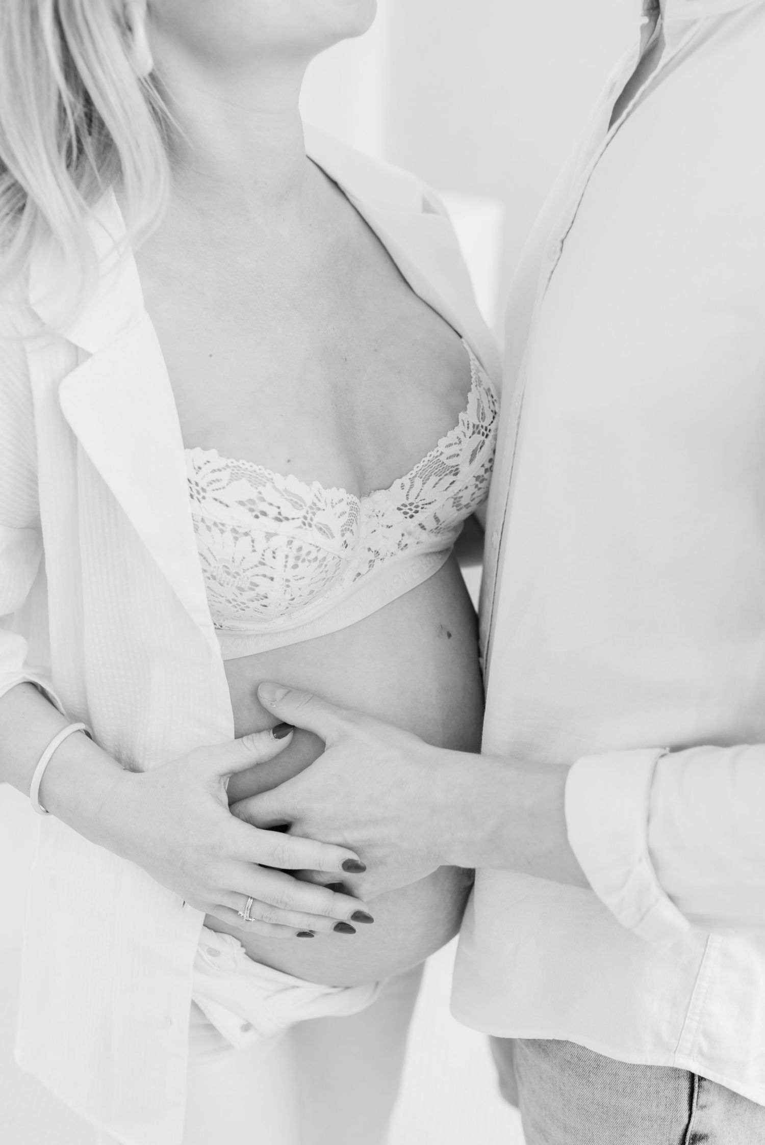 A romantic black and white photo showing a close embrace with a white button-down shirt and delicate lace bra.