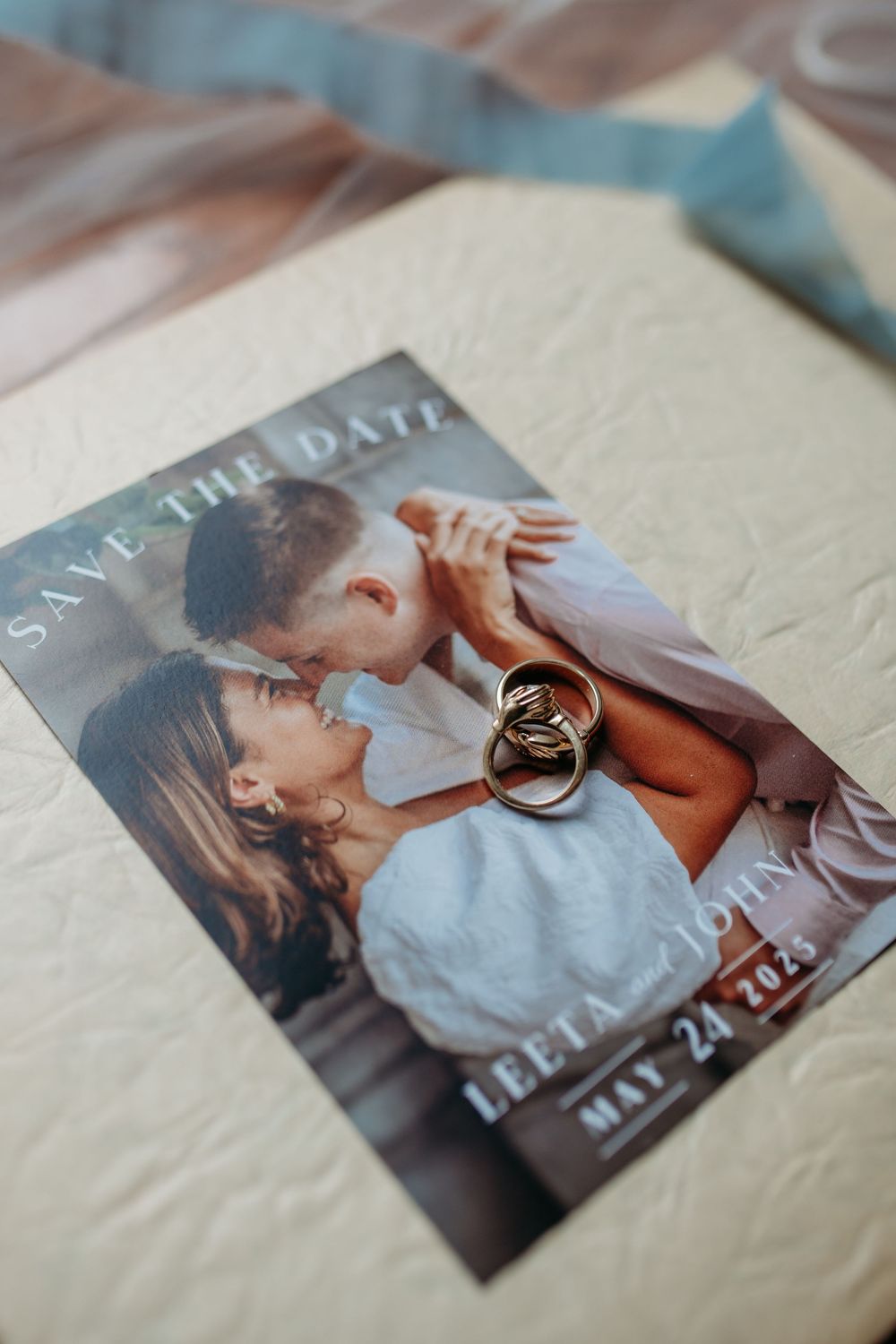 Save the date wedding announcement card with two wedding rings placed on top of a romantic photo.