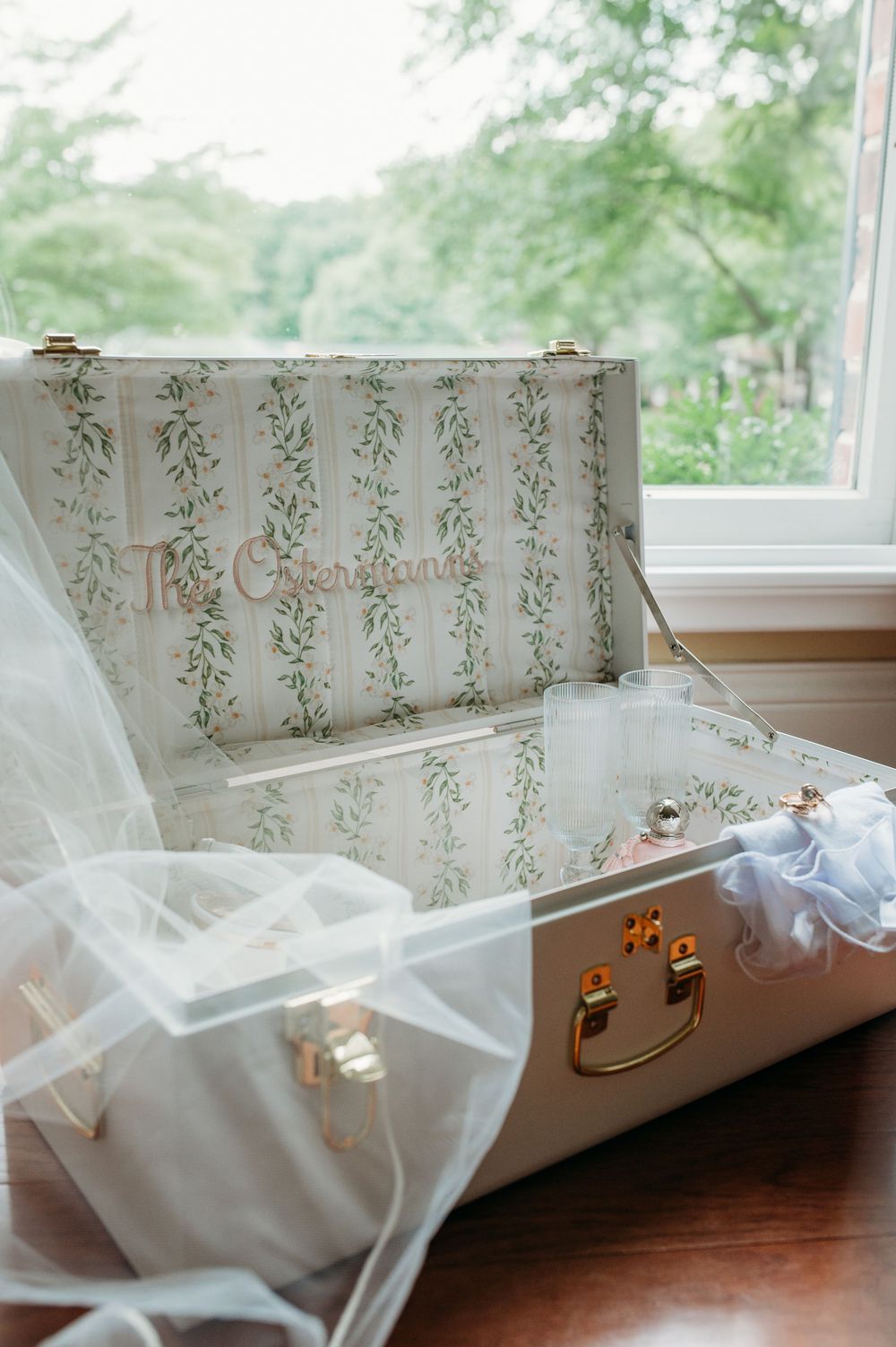Elegant window seat with floral wallpaper and sheer white curtains draped across creates a cozy reading nook.