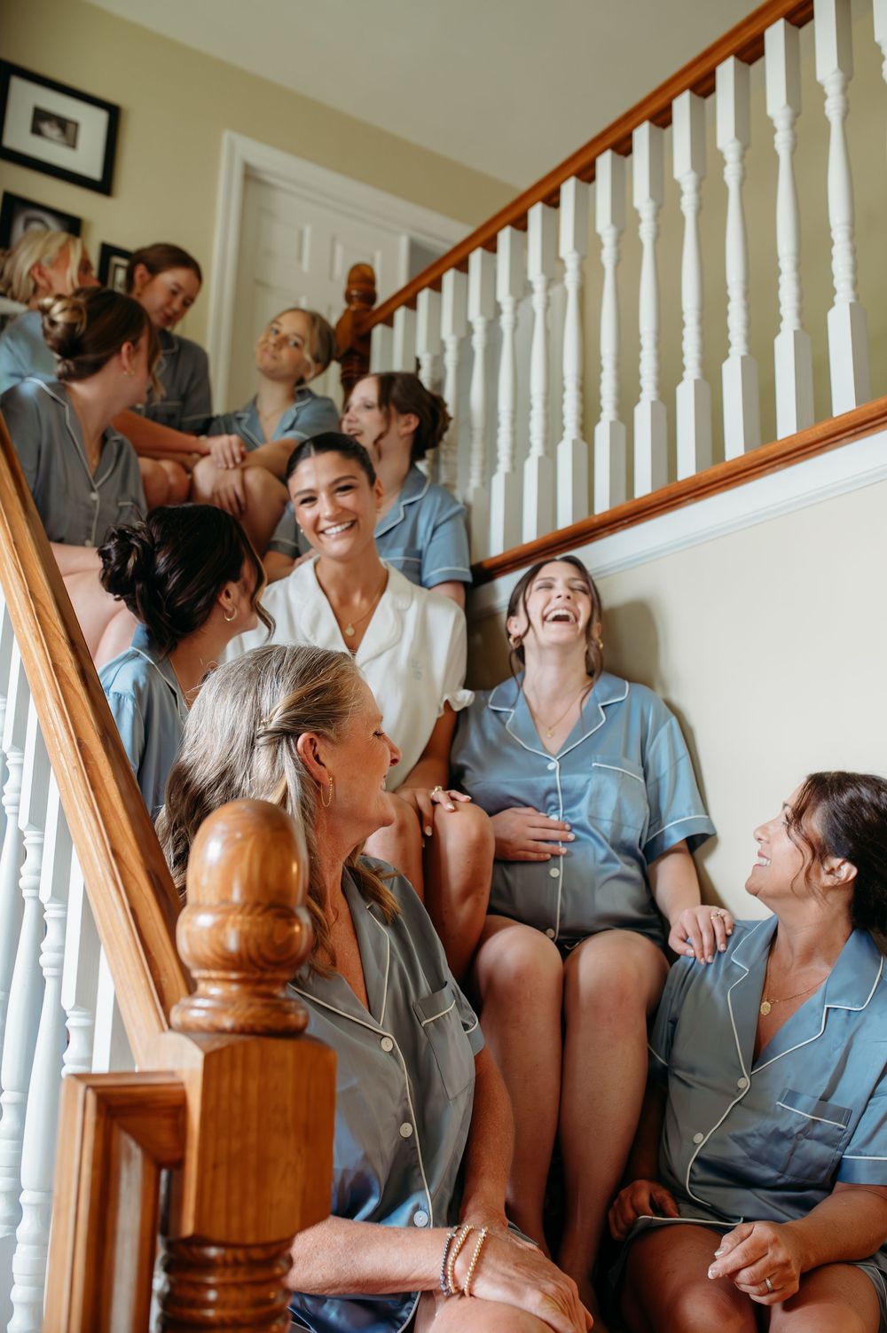 A group shares joyful laughter while sitting together on carpeted stairs in a casual gathering.