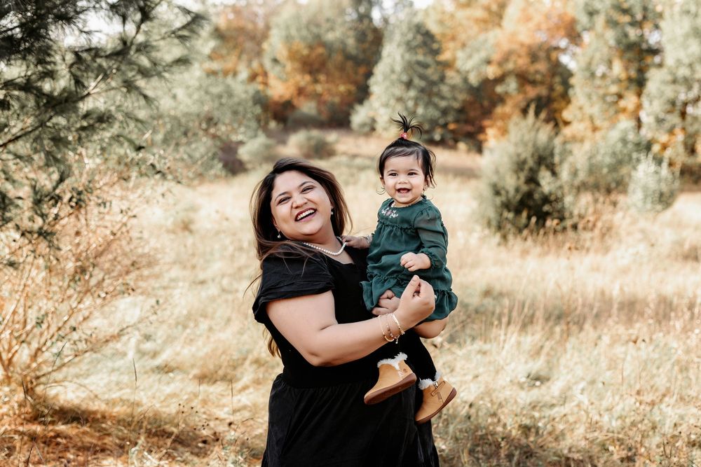 A joyful moment captured between mother and child outdoors in a sun-dappled autumn setting with golden grasses.