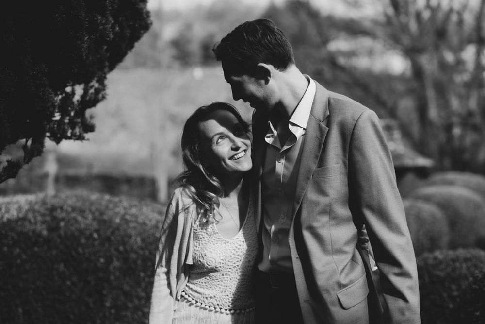 A romantic black and white photo shows a tender moment between a couple in a garden setting, creating an intimate atmosphere.