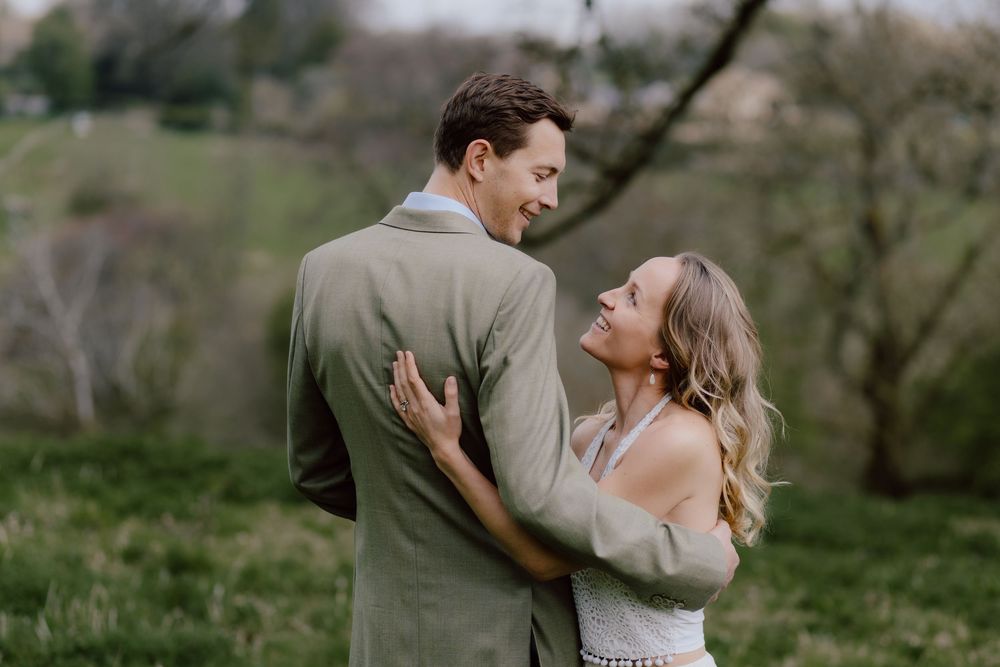 A couple embraces tenderly while laughing together in a natural outdoor setting.