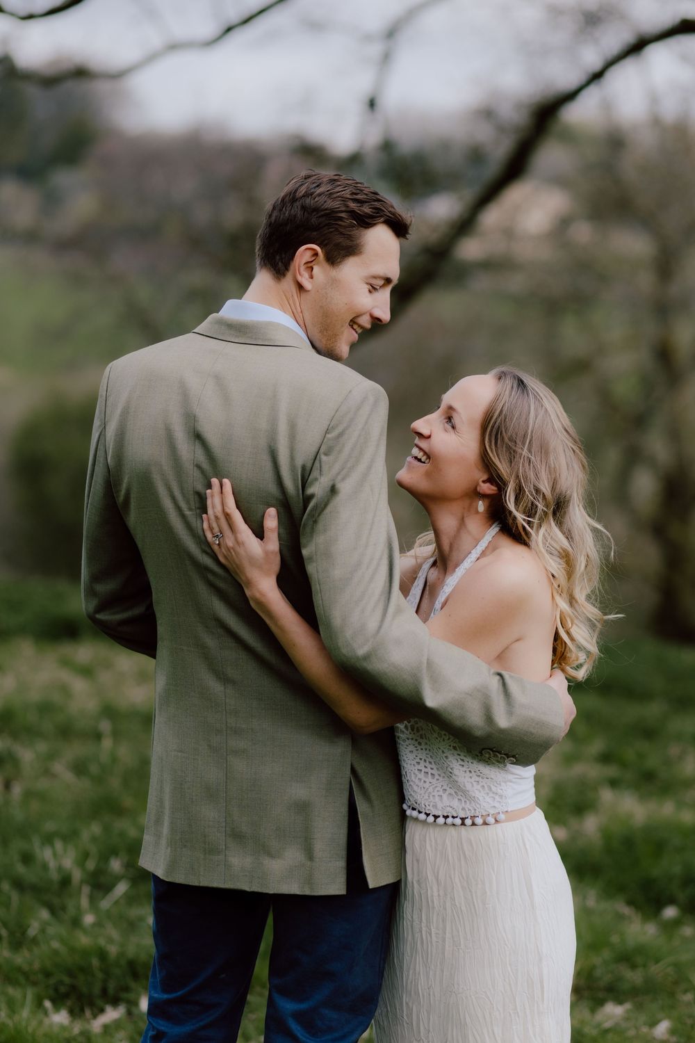 Happy newlywed couple share a joyful laugh while embracing in a garden setting.