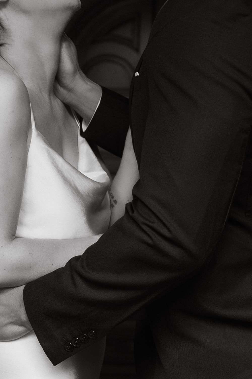 Black and white intimate portrait showing contrast between white dress and dark suit in an artistic composition.