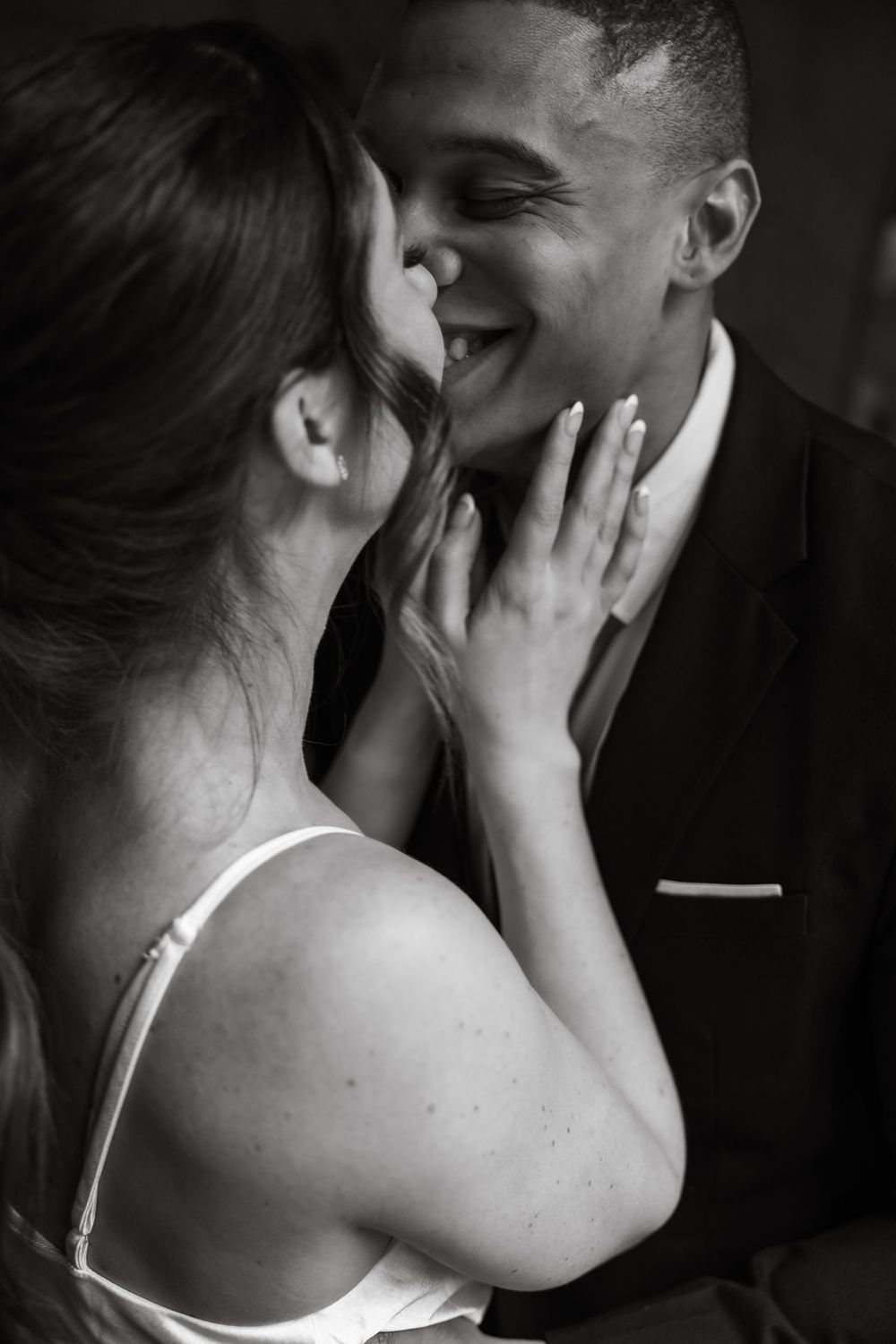 Intimate black and white portrait of couple sharing romantic moment in formal attire.