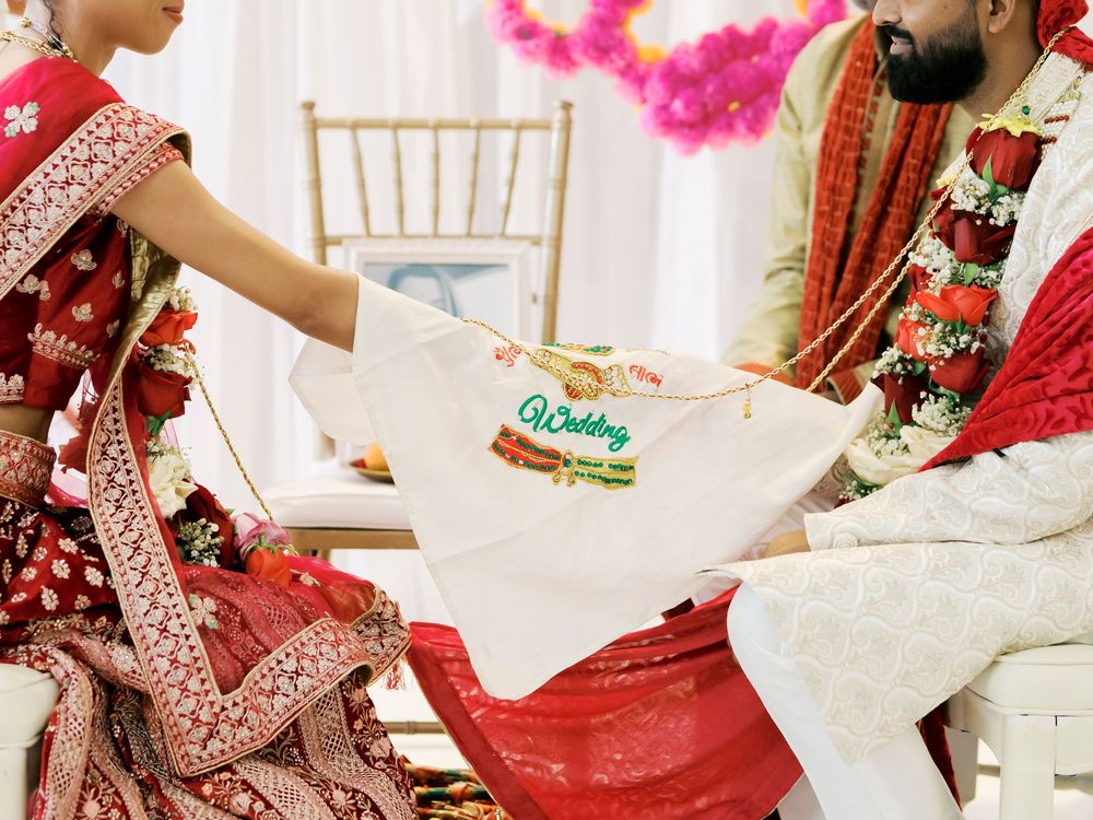 Traditional Indian wedding ceremony showing ritual exchange of items between bride and groom in red attire.