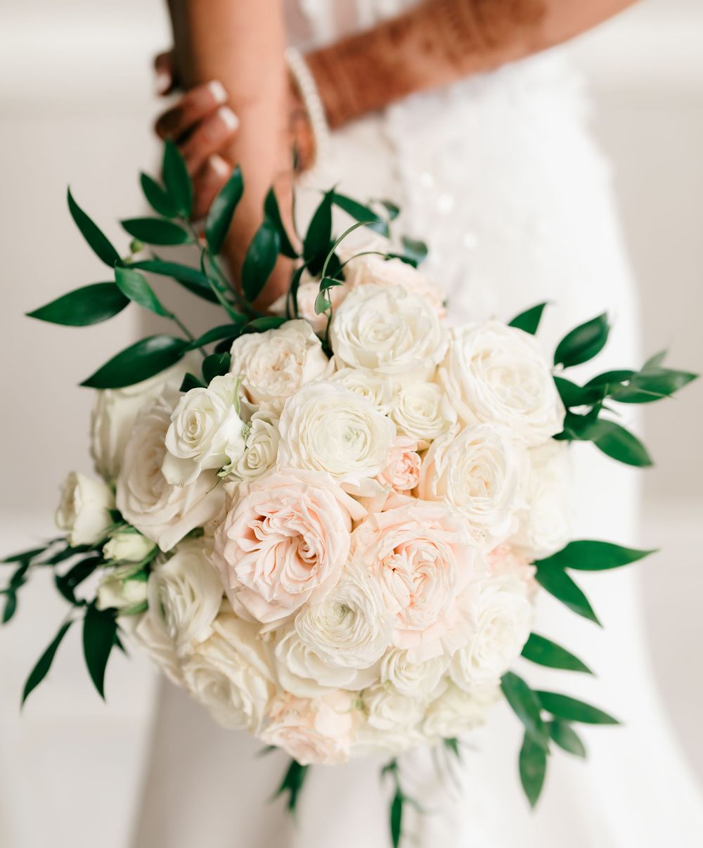 A stunning bridal bouquet with white and blush roses accented with green foliage.